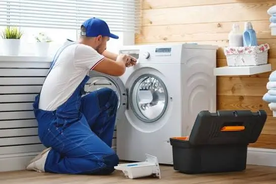 Technician checking modern washing machine drum